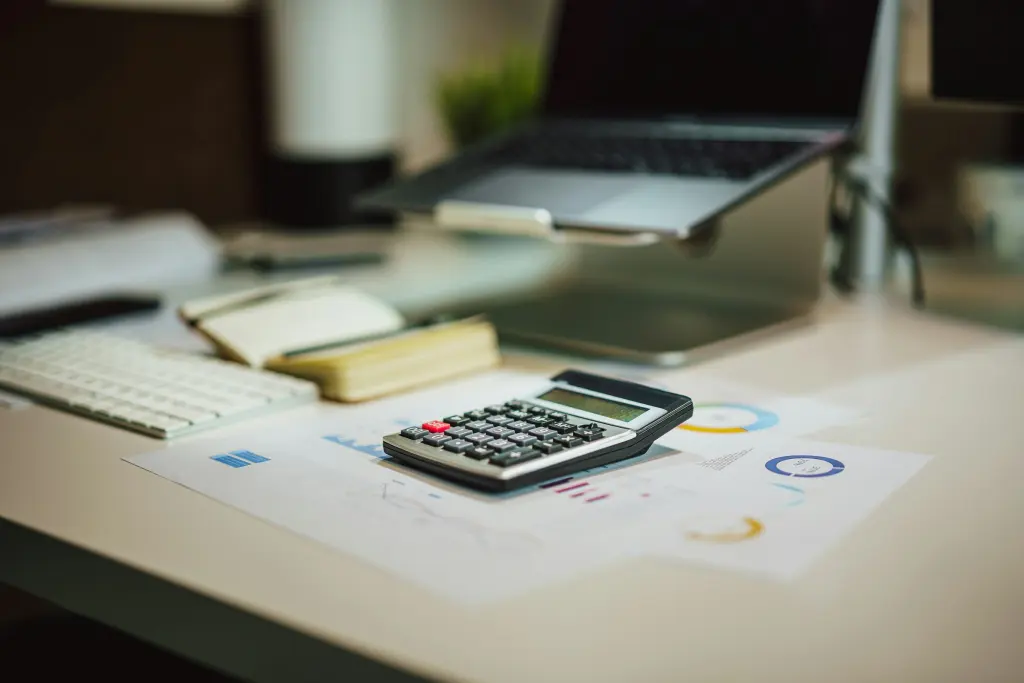 Calculadora y ordenador portátil sobre una mesa