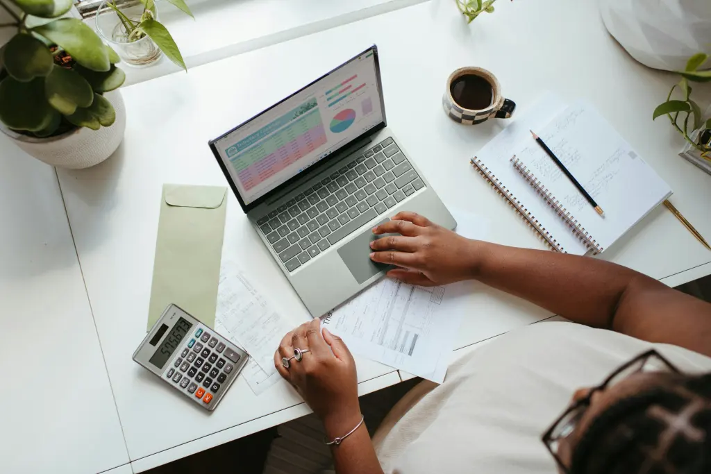 Persona trabajando con su portátil y una calculadora